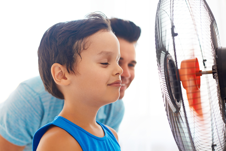 Deček in njegov oče stojita pred ventilatorjem