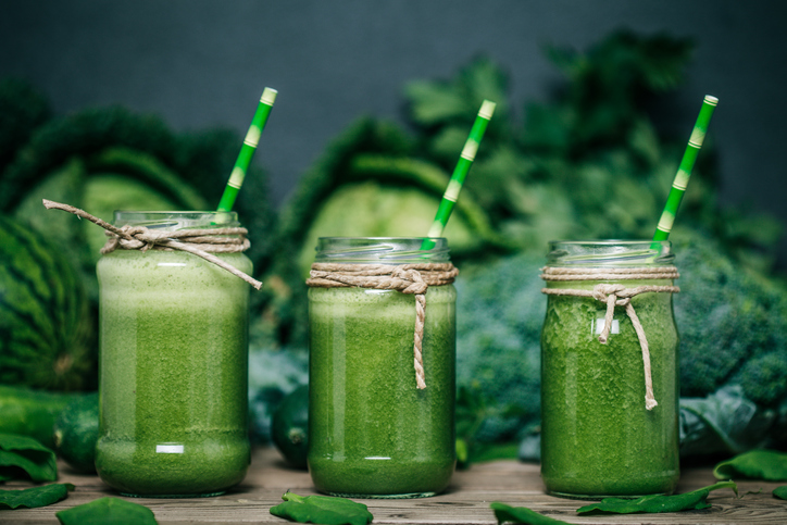 Zelenjavni zelenjavni smoothie, trije kozarci, zelje, brokoli in grah v ozadju