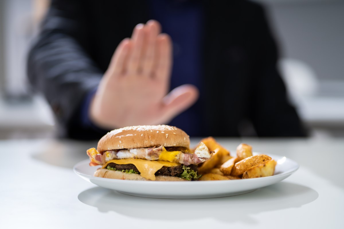 Neprimerna hrana kot vzrok zgage - hamburger na krožniku, ki ga človek zavrne